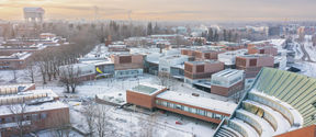 Drone image of Otaniemi campus in early December, light covering of snow everywhere, with low sun shining